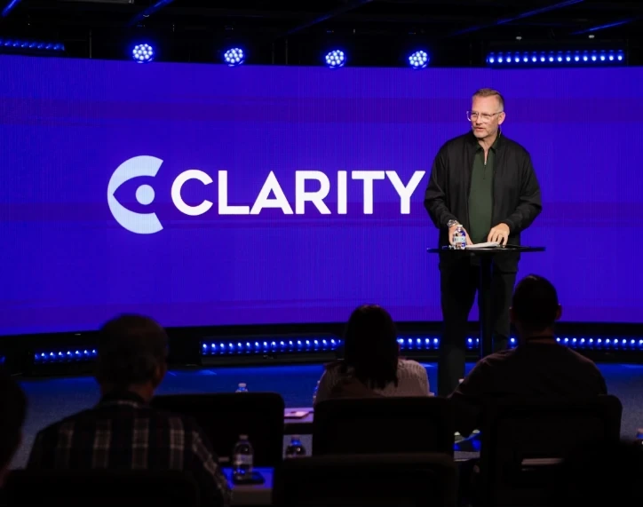 Mark Neal speaking on stage at a Clarity Leadership Collective event