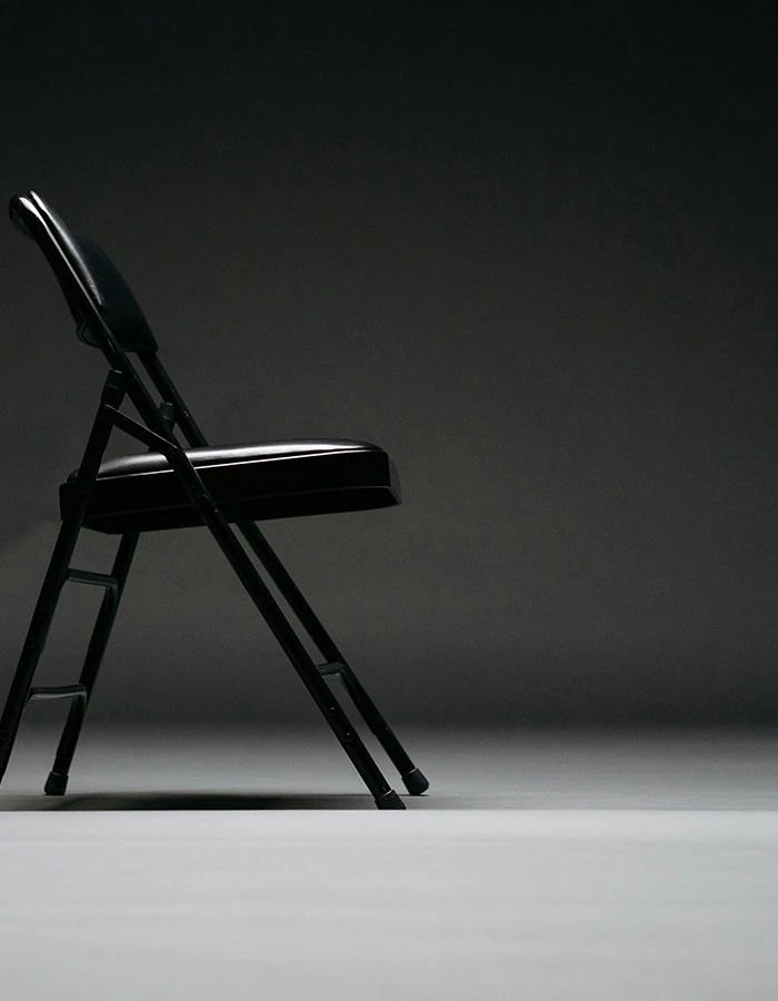 An empty folding chair under a spotlight